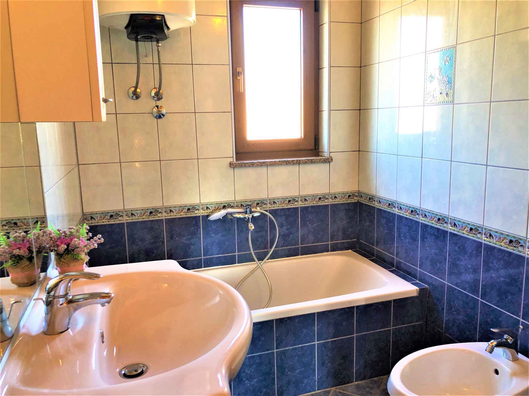 Un baño con lavamanos, bañera y ventana.