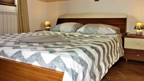 A neatly made bed with a patterned bedspread, two bedside lamps, and a wooden headboard. - Holiday apartment with balcony and sea view (Medulin)
