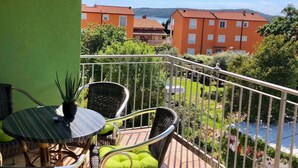 A balcony with wicker furniture and a view of buildings and a body of water. - Holiday apartment with balcony and sea view (Medulin)