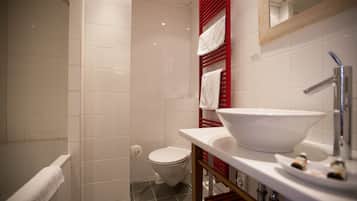 A modern bathroom with a white sink, a red towel rack, and a shower area.