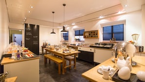 A modern kitchen with wooden countertops, a dining area with a bench, and a large window with blinds.