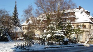 A snow-covered house with a large garden and a gazebo.