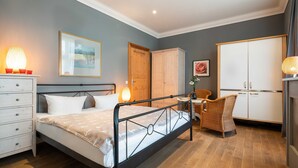 A bedroom with a bed, dresser, wardrobe, and a chair.