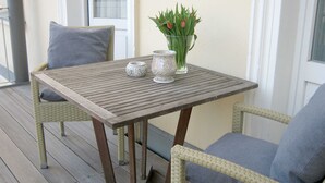 A wooden table with two chairs on a balcony.