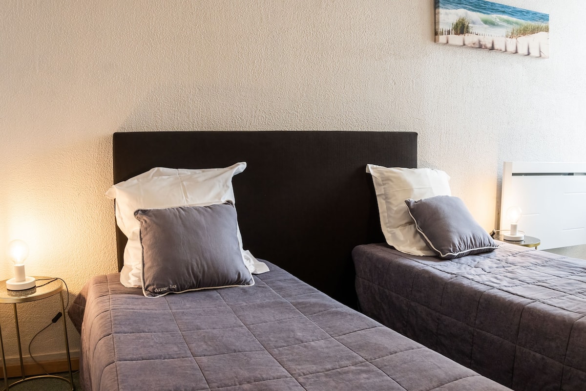 Un lit double avec une tête de lit noire, deux oreillers et une lampe de chevet.
