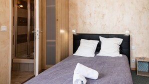 Ein Hotelzimmer mit einem Bett, einer Dusche und einer Holzwand.