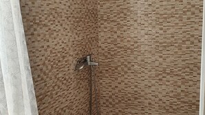 A bathroom with a tiled shower wall, a toilet, and a showerhead. - Kumbaz Pansiyon (Sapanca)