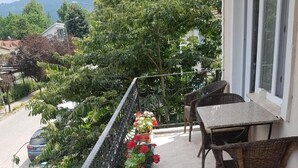 A balcony with wicker furniture, potted plants, and a view of the street and greenery. - Kumbaz Pansiyon (Sapanca)