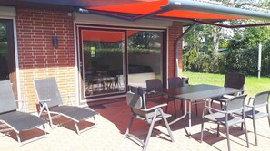 An outdoor patio with a brick wall, sliding glass doors, and a table with chairs.