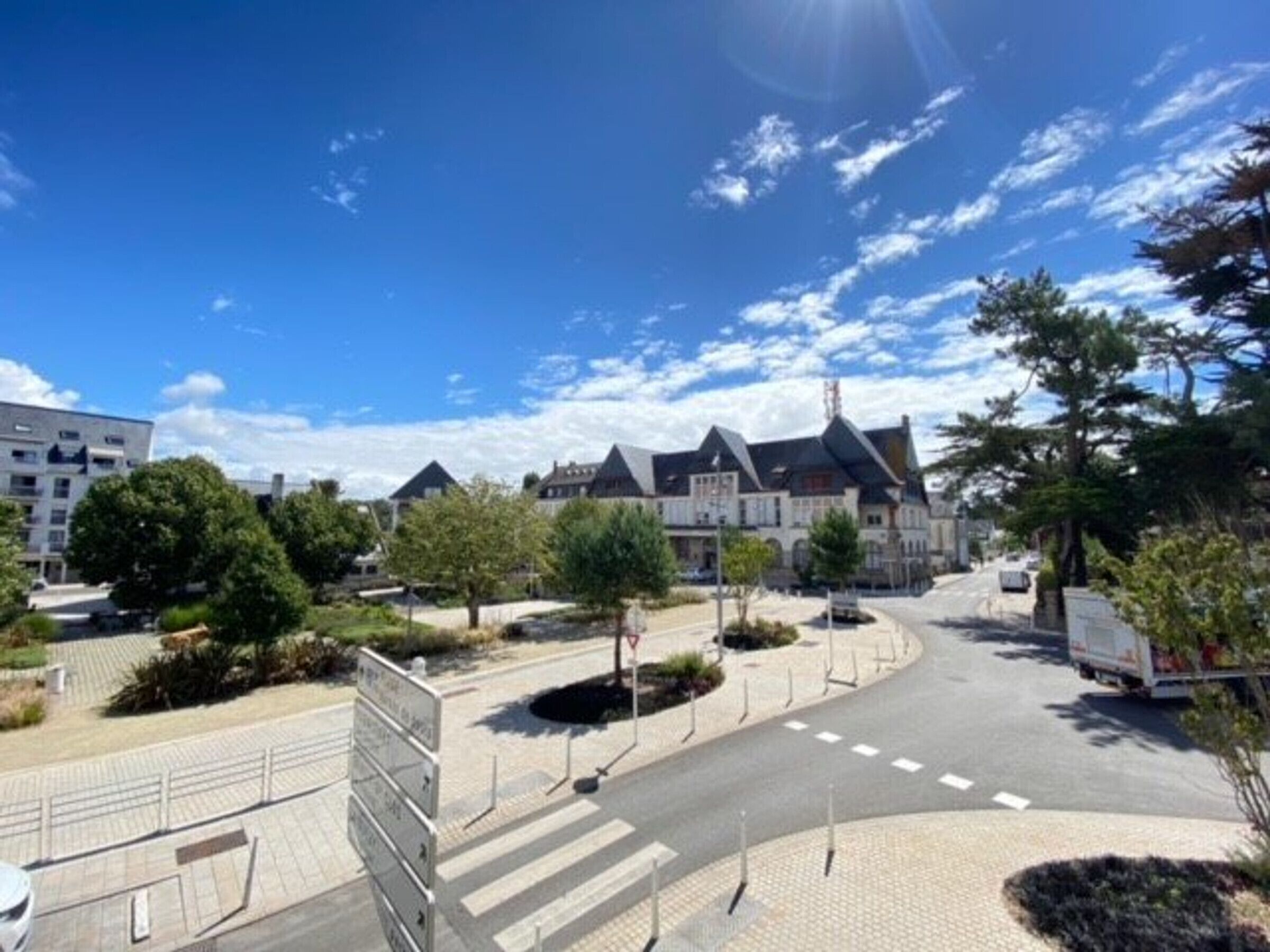 Un barrio residencial con una calle pavimentada, un paso de peatones y una combinación de casas modernas y tradicionales.