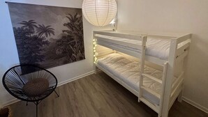 A bunk bed with a hanging light fixture, a wall-mounted picture, and a black chair. - Cozy 2-Room Apartment, 250m from Beach, Terrace, Private Parking, Sleeps 4 (Port-la-Nouvelle)