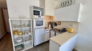 A compact kitchen with white cabinetry, a microwave, a refrigerator, and a sink. - Cozy 2-Room Apartment, 250m from Beach, Terrace, Private Parking, Sleeps 4 (Port-la-Nouvelle)