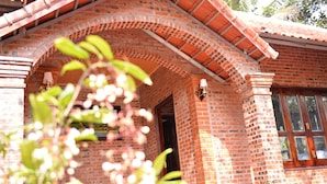 Un edificio de ladrillo con una entrada de arco grande, una ventana con marco de madera y una planta en maceta cerca de la entrada.
