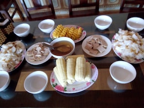A dining table with various dishes including corn on the cob, tofu, and other food items.