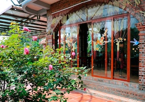 A traditional building with a brick facade, large glass windows, and a tiled patio area.