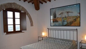 Ein Schlafzimmer mit einem Bett, einem Gemälde, einem Fenster und einer Lampe.