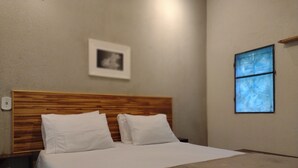 Siististi pedattu sänky valkoisilla vuodevaatteilla hotellihuoneessa.