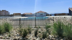 A pool area with a wooden fence, rocks, and desert plants. - Elevated Ground Floor Apartment, 3 Rooms, 6 Sleeps, Pool, Terrace, Parking, Sports Facilities (Port Barcarès)