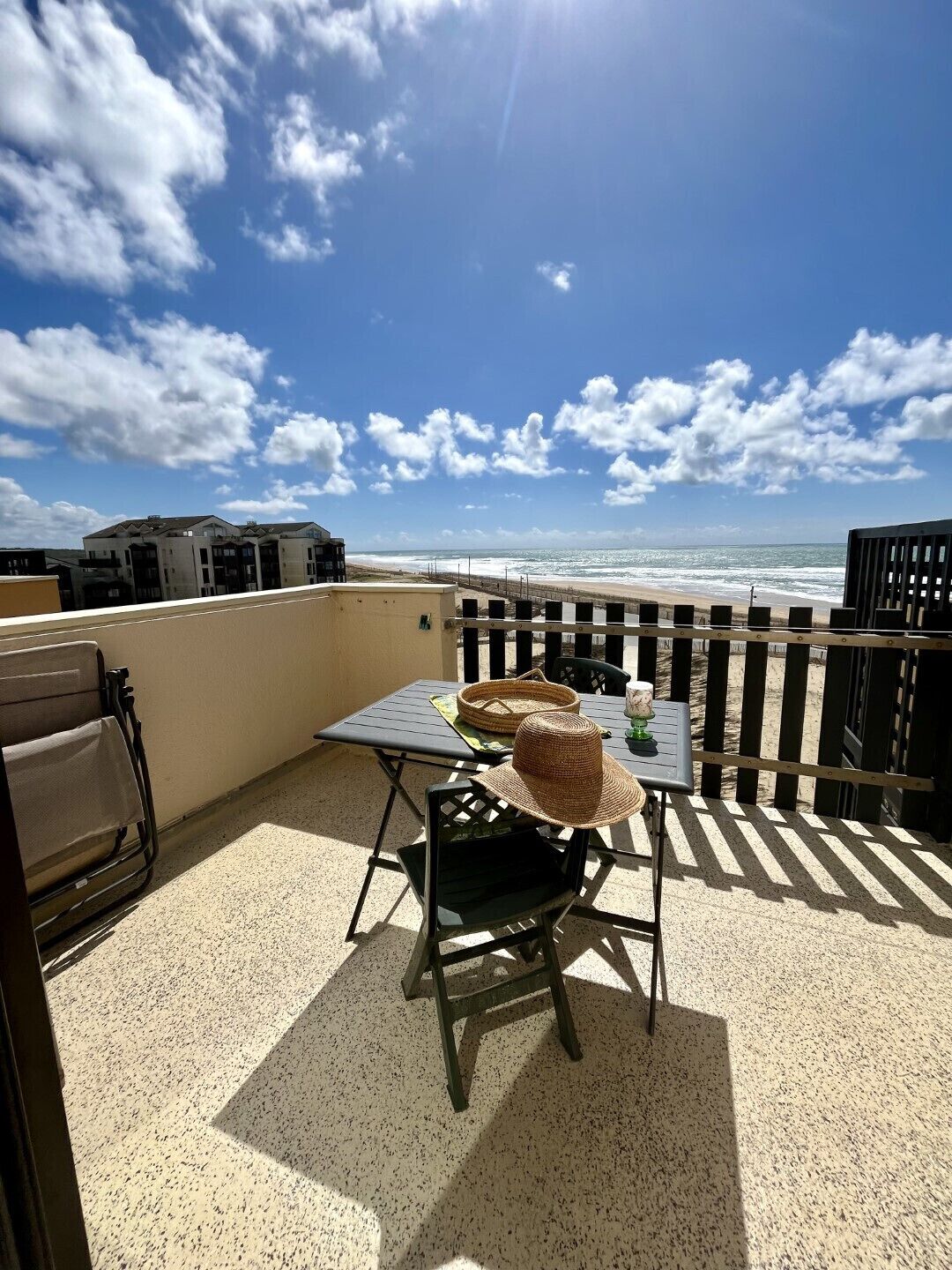 A patio with a table and chairs, overlooking a beach.