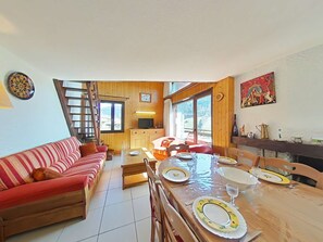Un intérieur chaleureux avec un canapé, une table à manger pour quatre personnes et un coin cuisine.