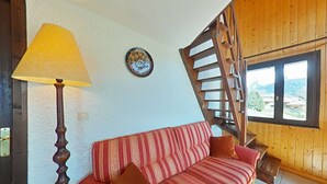 Ein gemütliches Zimmer mit einer Holztreppe, einem Sofa mit gestreiften Kissen, einer Lampe und einer dekorativen Platte an der Wand.