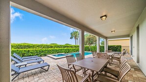 An outdoor patio with a pool, lounge chairs, and a dining table. - 10 min to Disney, private pool home on luxury resort, brand new hardwood floors. (kissimmee)