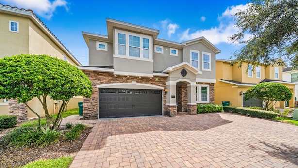 A residential house with a brick driveway, a garage, and a well-maintained lawn. - 10 min to Disney, private pool home on luxury resort, brand new hardwood floors. (kissimmee)
