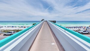 A boardwalk leading to a beach with umbrellas and beachgoers.