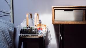 A small bedside table with a basket containing a bottle, a jar, and a bag. - Ciccio B&B (Bergamo)