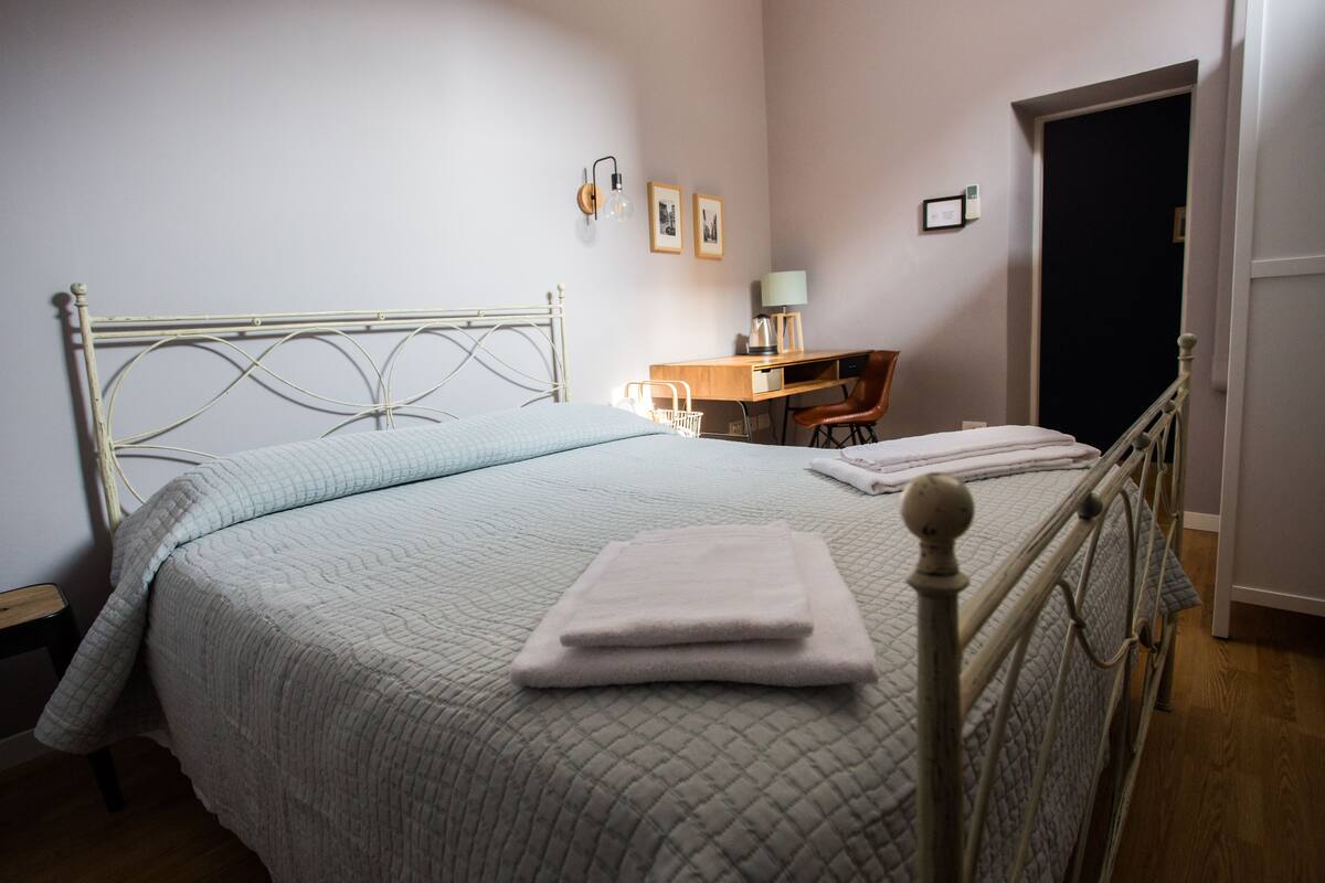 Un lit bien fait, avec une couvre-lit matelassé, une table de chevet avec une lampe et une chaise.