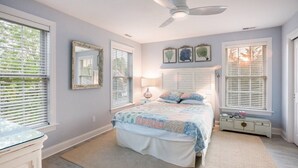 A bedroom with a bed, a nightstand, a dresser, a ceiling fan, and three framed pictures on the wall.