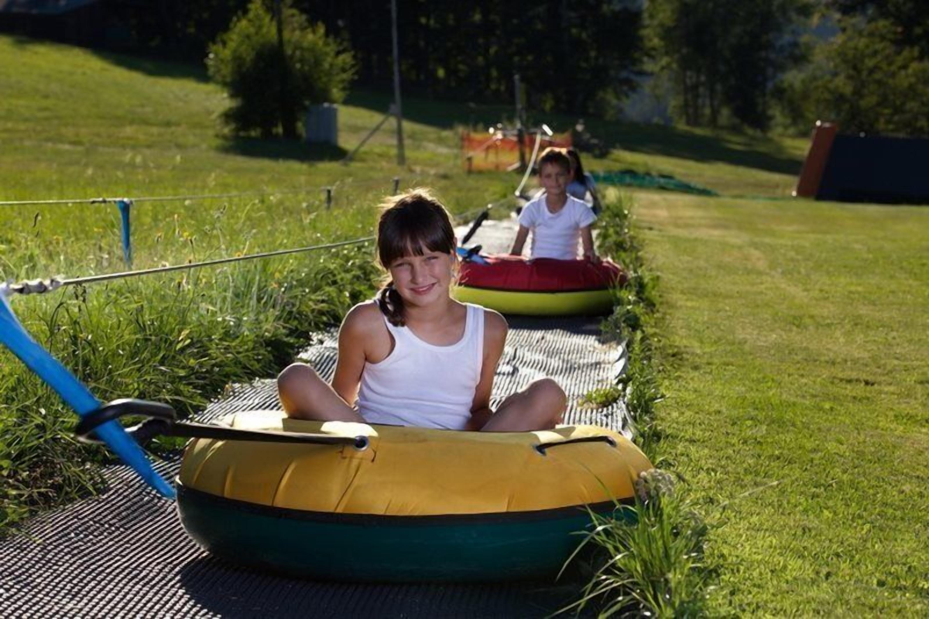 A grassy area with inflatable rafts and a blue hose.