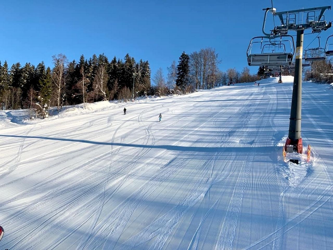 A ski slope with a chairlift and trees in the background.