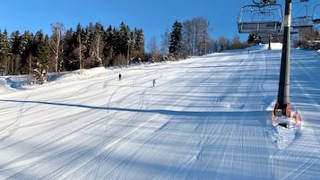 A ski slope with a chairlift and trees in the background.