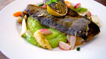 Un plato de comida con pescado, aguacate, rábano y limón.