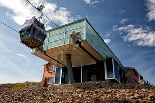 Um edifício moderno com teleférico, base de pedra e céu limpo.