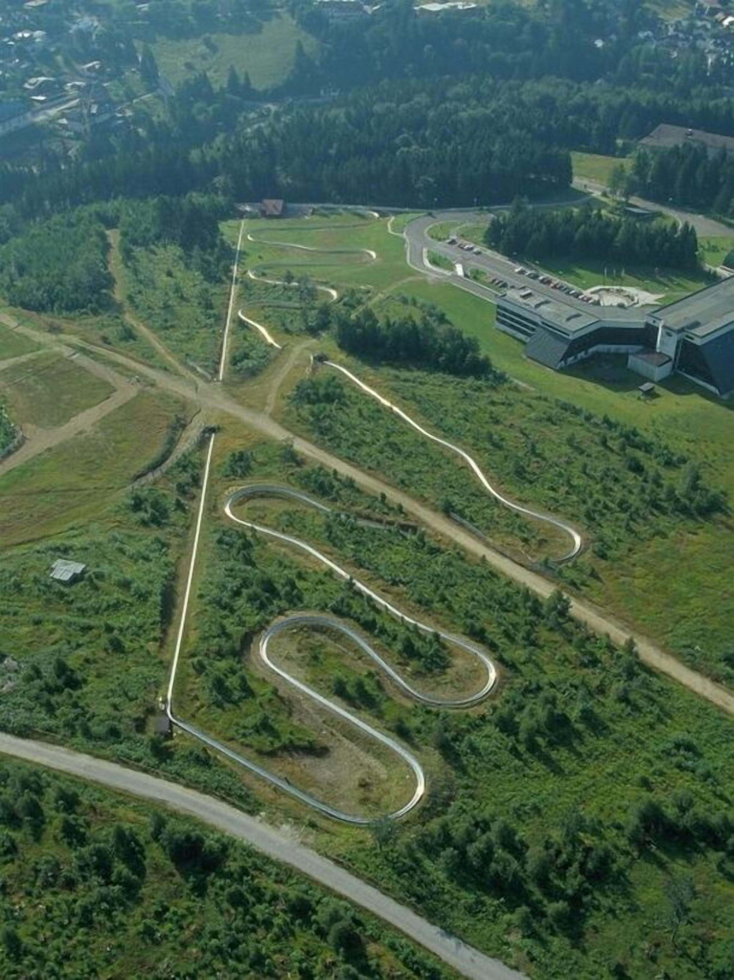 An aerial view of a winding road layout with a large building complex in the background.