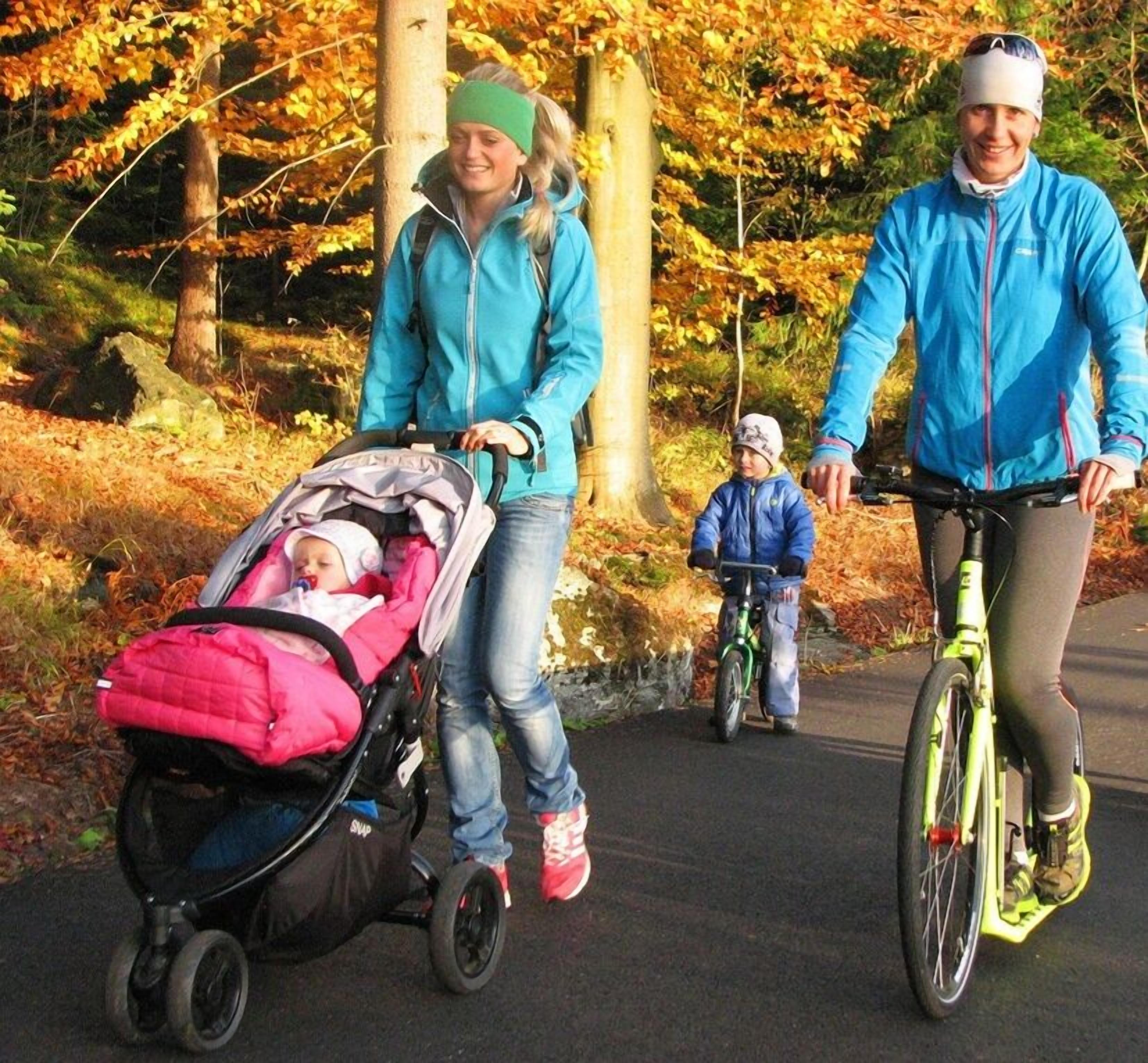 A family on a paved path with a stroller and a bicycle.