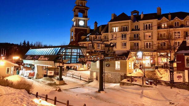 Una plaza histórica con una imponente torre del reloj, una zona de mercado cubierta y edificios tradicionales.