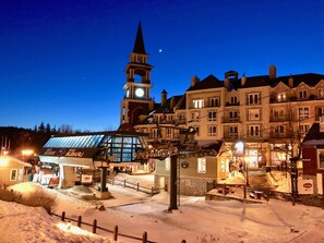 A historic town square with a prominent clock tower, a covered market area, and traditional buildings.