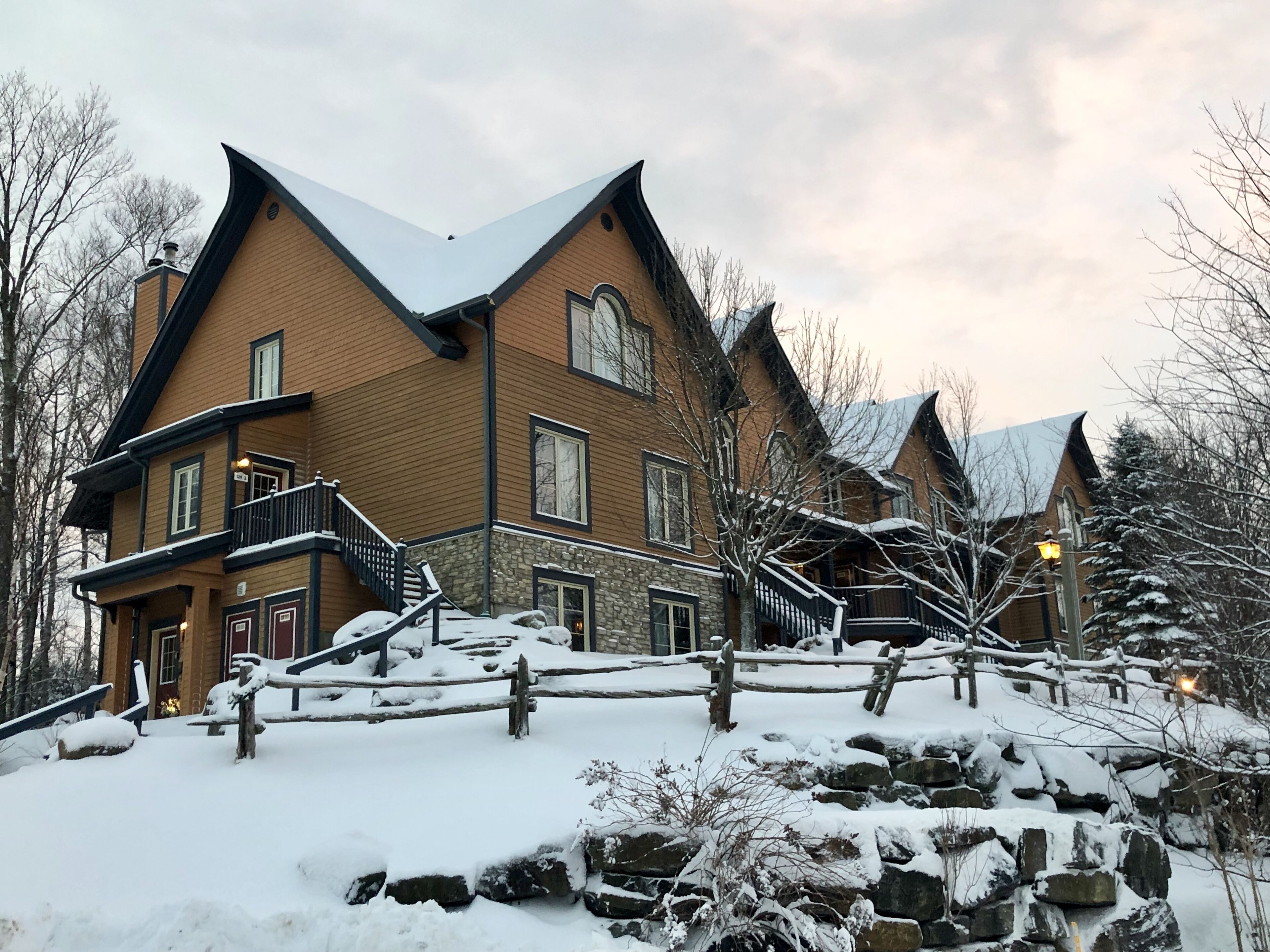 A large, multi-story building with a steeply pitched roof, stone foundation, and wooden exterior.