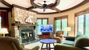 Una sala de estar con chimenea de piedra, televisor y asientos cómodos.