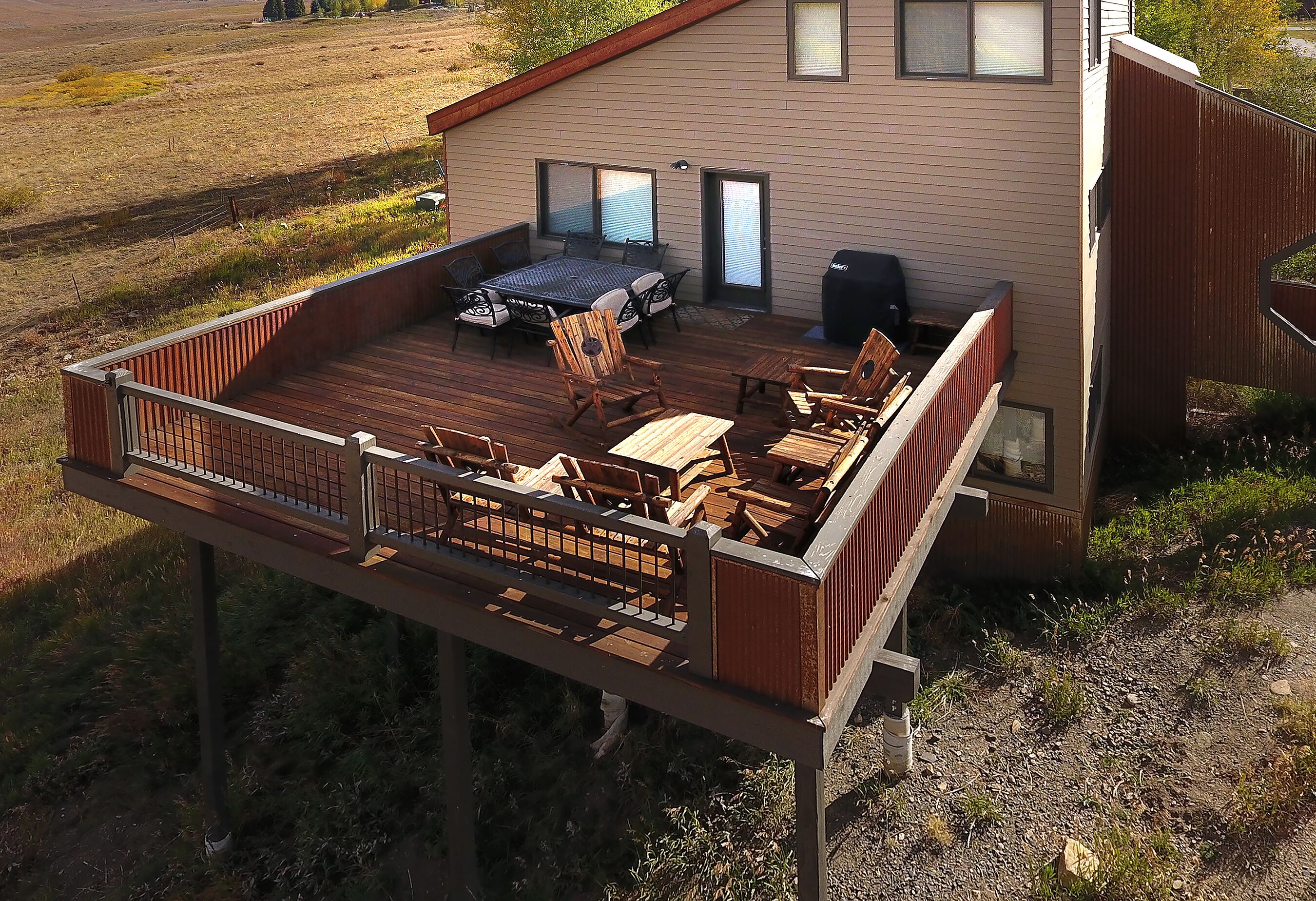 A deck with outdoor furniture, a grill, and a view of a rural landscape.