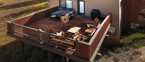A deck with outdoor furniture, a grill, and a view of a rural landscape.