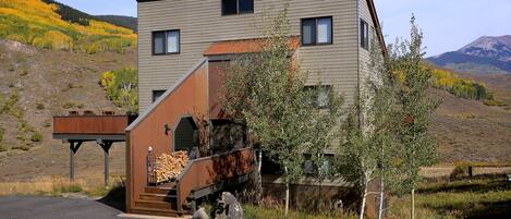 Un bâtiment moderne à deux étages, doté d’une terrasse en bois et d’un petit escalier menant à la porte d’entrée.