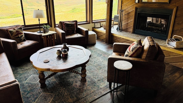 Un salon chaleureux avec une cheminée, de grandes fenêtres et un décor rustique.