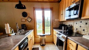Una cocina con armarios de madera, un microondas de acero inoxidable y un ventanal grande.