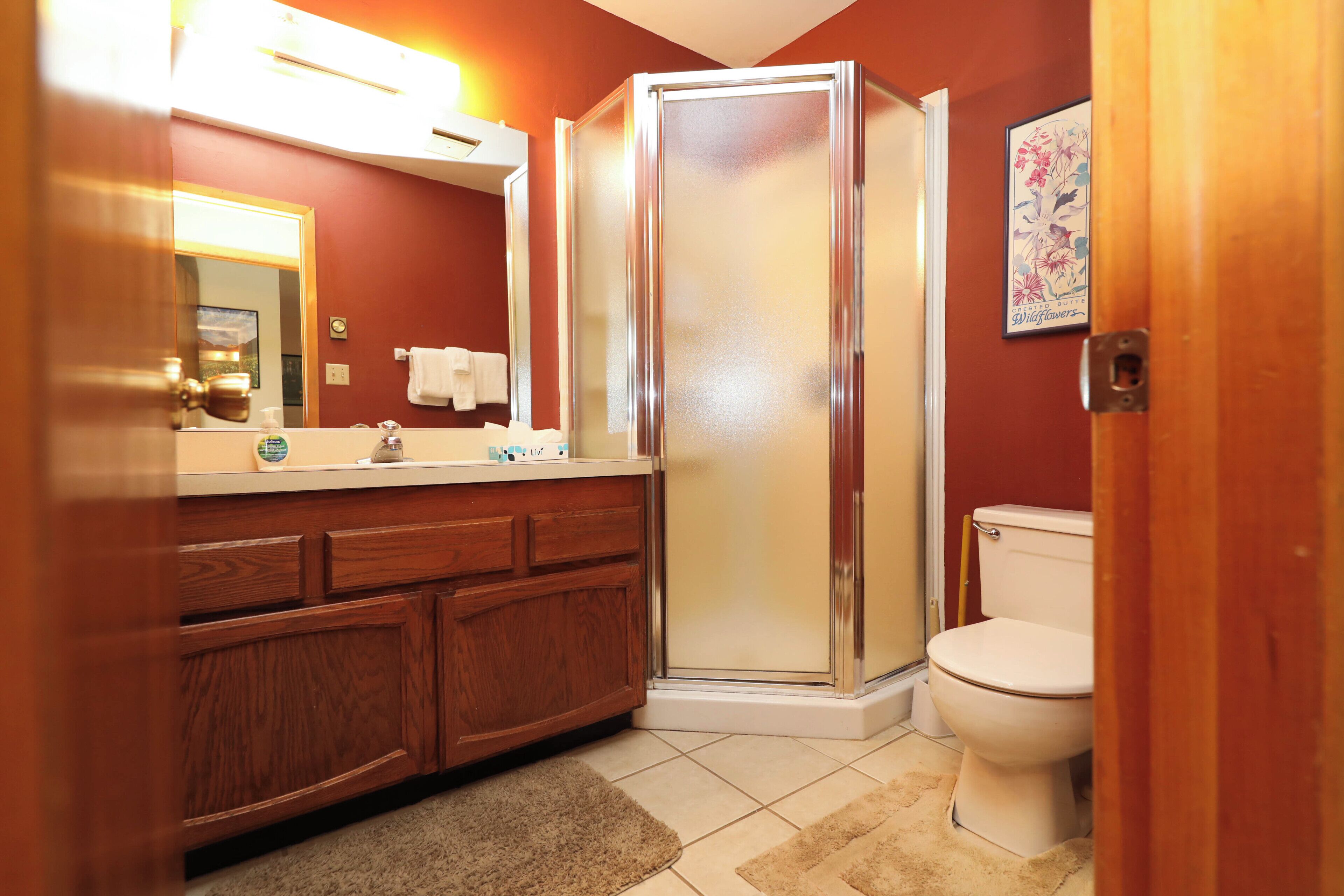 A bathroom with a wooden vanity, a glass shower enclosure, and a toilet.