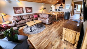 A cozy living room with a wooden ceiling, a sofa set, a coffee table, and a dining area with chairs. - Mt CB Home | 3 Bedroom | Hot Tub | Gas Grill | Mt CB View | Second Living Room (Mt. Crested Butte)