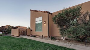 A modern building with a flat roof, a large window, and a well-maintained lawn.